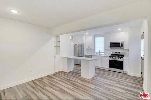 kitchen with backsplash, appliances with stainless steel finishes, light wood-type flooring, and white cabinets