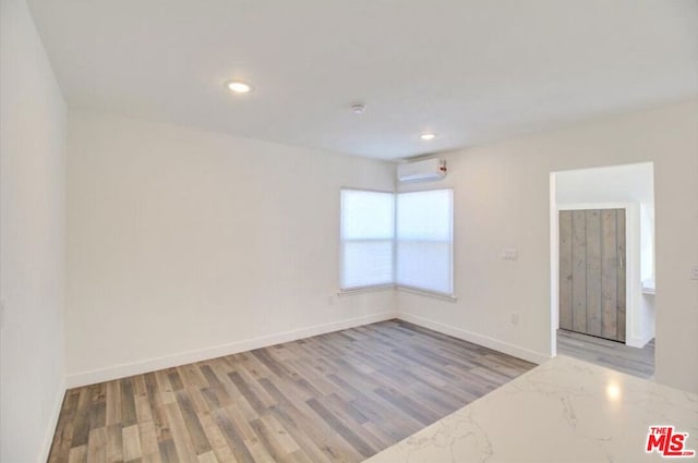 unfurnished room with wood-type flooring and a wall unit AC