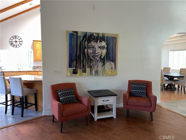 living area with beam ceiling, high vaulted ceiling, and dark hardwood / wood-style flooring