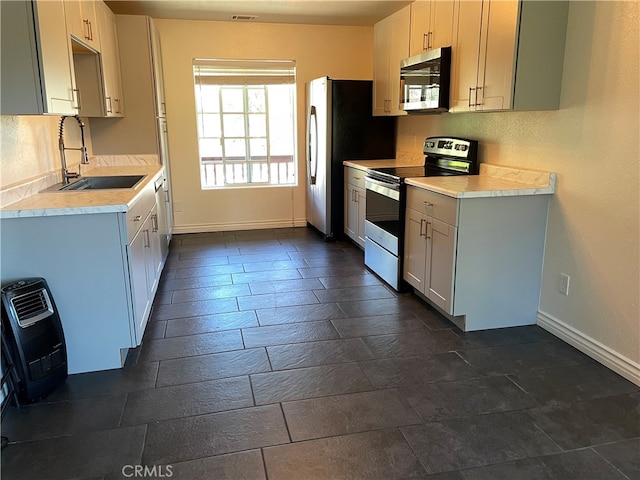 kitchen with appliances with stainless steel finishes, sink, and white cabinets