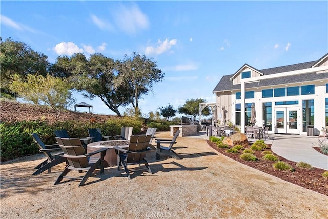 view of patio / terrace featuring an outdoor kitchen, french doors, and an outdoor fire pit