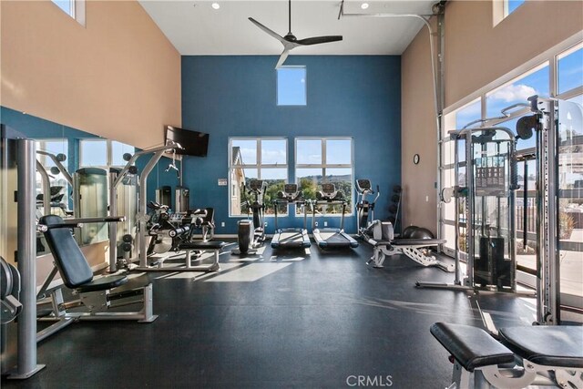 exercise room featuring ceiling fan, plenty of natural light, and a towering ceiling