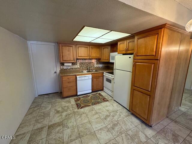 kitchen featuring sink, backsplash, and white appliances