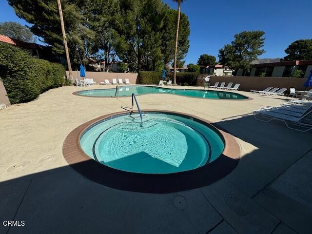 view of pool with a hot tub and a patio