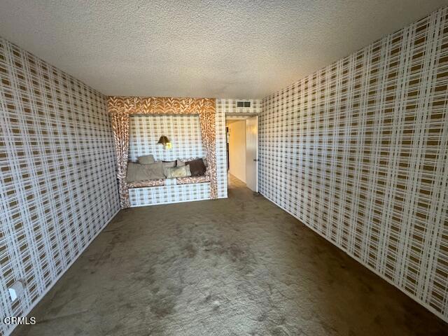 interior space with a textured ceiling and carpet floors