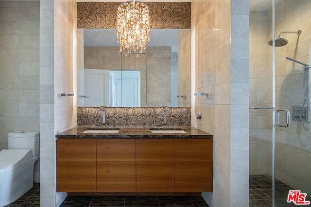 bathroom with vanity, backsplash, tile walls, a notable chandelier, and an enclosed shower