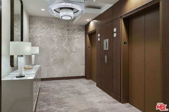 corridor featuring elevator, light colored carpet, and an inviting chandelier