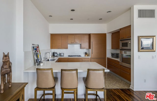 kitchen featuring kitchen peninsula, a kitchen breakfast bar, dark hardwood / wood-style floors, and stainless steel appliances