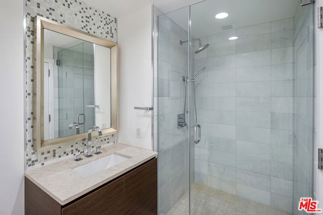 bathroom featuring decorative backsplash, vanity, and an enclosed shower