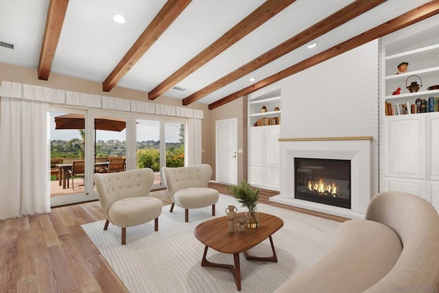 living room with vaulted ceiling with beams, a large fireplace, and light hardwood / wood-style flooring