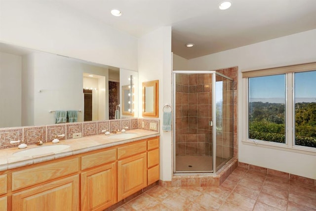 bathroom featuring tile patterned flooring, vanity, a shower with door, and tasteful backsplash