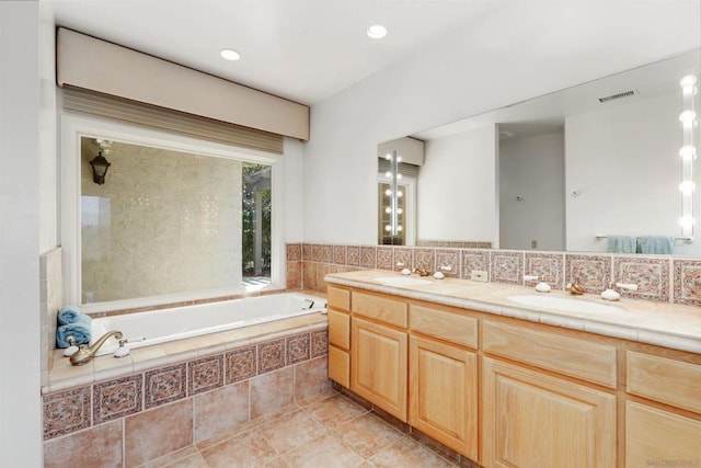 bathroom with vanity and tiled tub