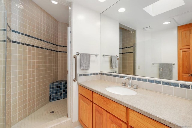 bathroom featuring tasteful backsplash, a skylight, vanity, and tiled shower