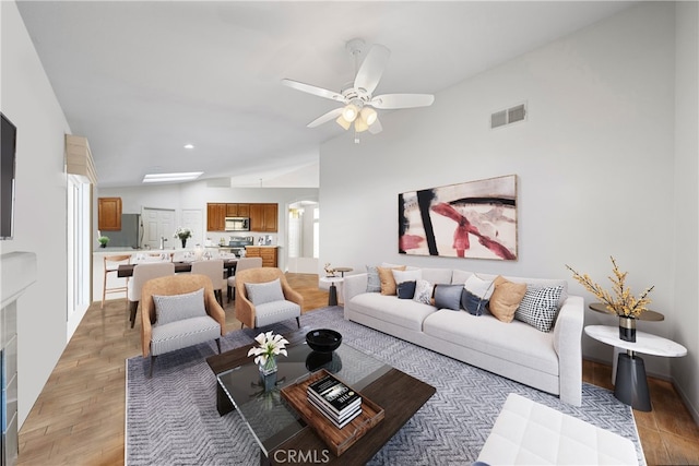 living room with lofted ceiling, light wood-type flooring, and ceiling fan