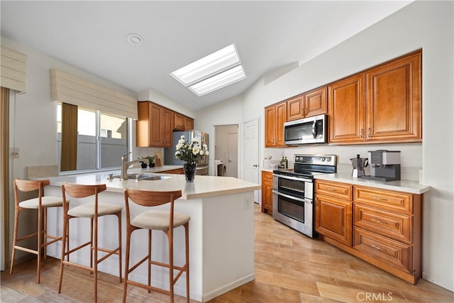 kitchen featuring kitchen peninsula, light hardwood / wood-style floors, stainless steel appliances, lofted ceiling, and a breakfast bar