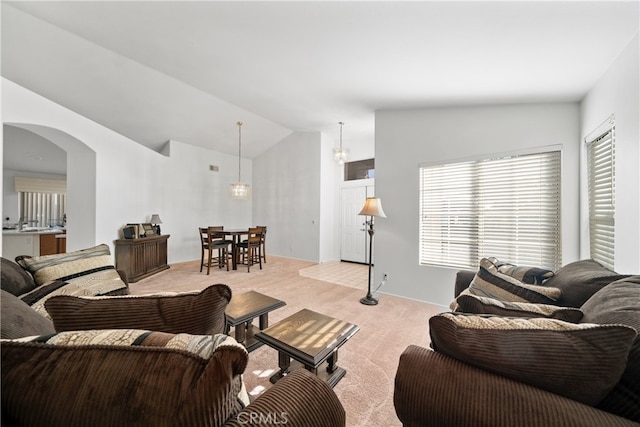 carpeted living room featuring vaulted ceiling and a notable chandelier