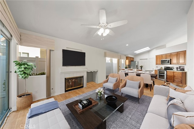 living room with light hardwood / wood-style flooring, lofted ceiling, a fireplace, and ceiling fan