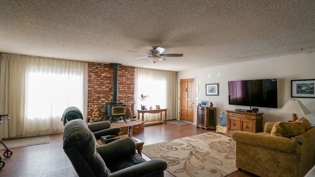 living room featuring hardwood / wood-style floors, a textured ceiling, a wood stove, and ceiling fan