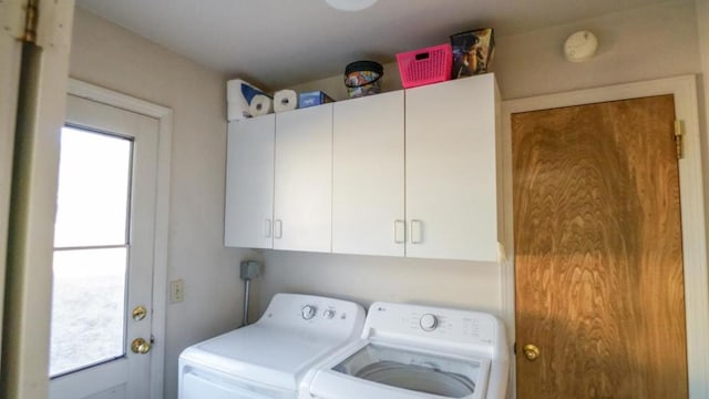 clothes washing area featuring cabinets and washer and dryer