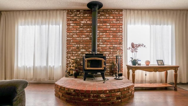 living area with a wood stove, a textured ceiling, plenty of natural light, and hardwood / wood-style floors