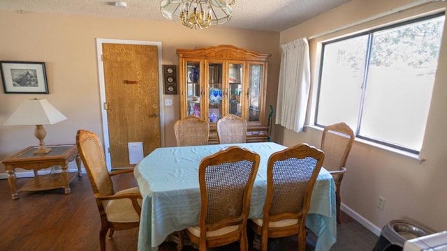 dining room with dark wood-type flooring and an inviting chandelier