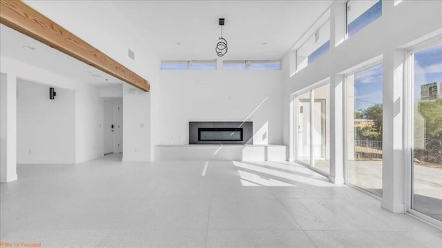 unfurnished living room featuring beam ceiling and a towering ceiling