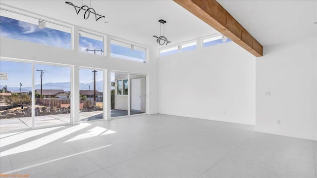 interior space featuring beamed ceiling, plenty of natural light, a high ceiling, and a notable chandelier