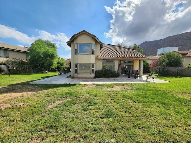 back of property featuring a mountain view, a patio area, and a lawn