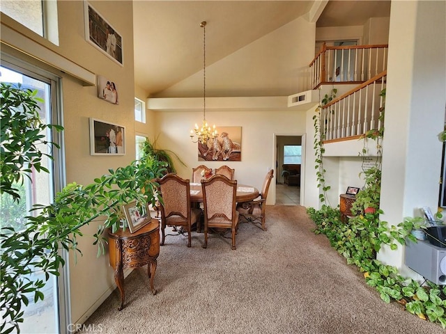 carpeted dining area with high vaulted ceiling and an inviting chandelier