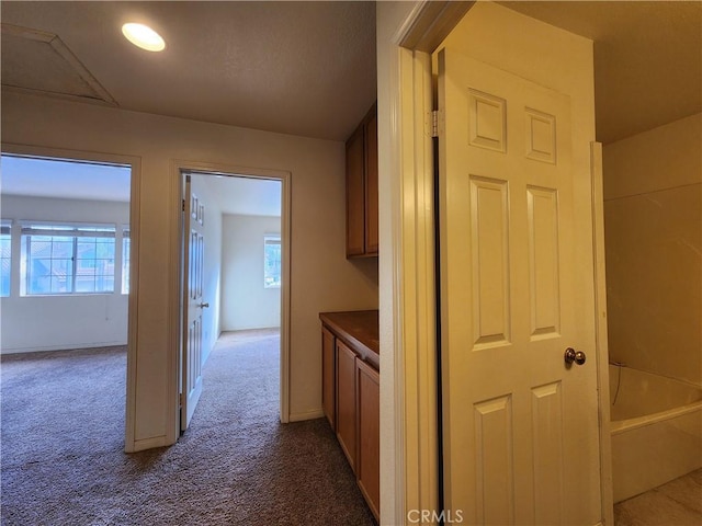 hall with baseboards and dark carpet