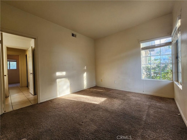 spare room featuring baseboards, light tile patterned flooring, visible vents, and light colored carpet