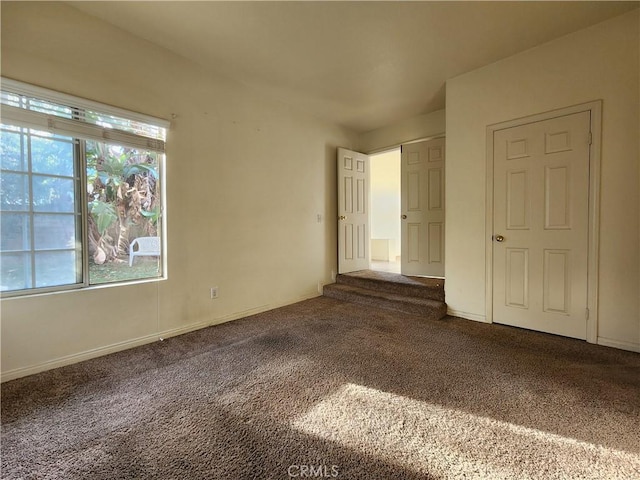 unfurnished bedroom featuring dark colored carpet and baseboards