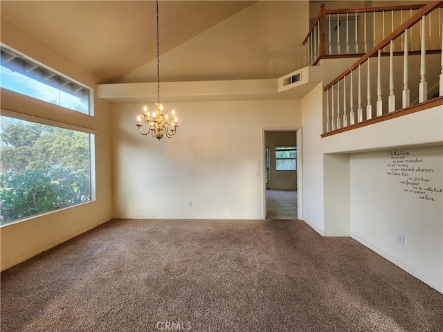 spare room featuring carpet, visible vents, an inviting chandelier, high vaulted ceiling, and baseboards