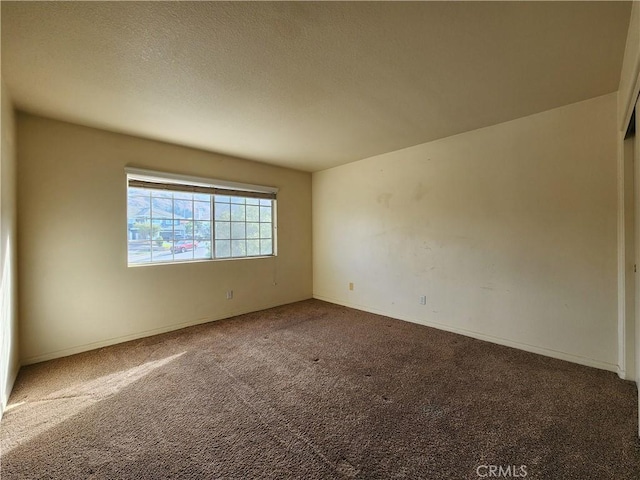 unfurnished room featuring carpet, baseboards, and a textured ceiling