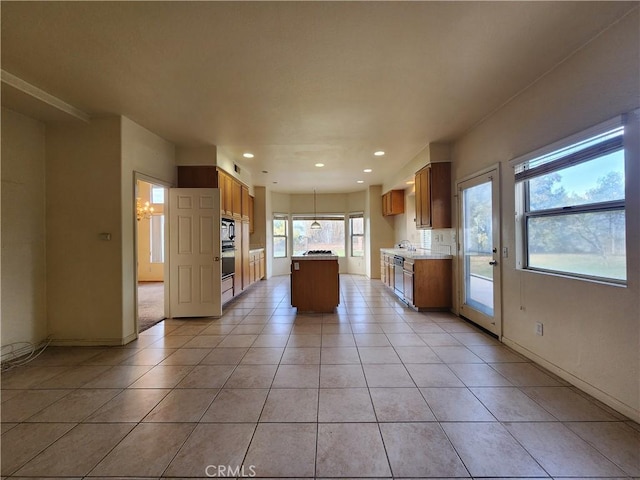 kitchen with light tile patterned floors, recessed lighting, a kitchen island, light countertops, and brown cabinetry