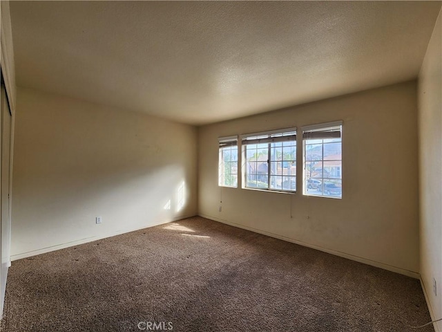 carpeted empty room with a textured ceiling