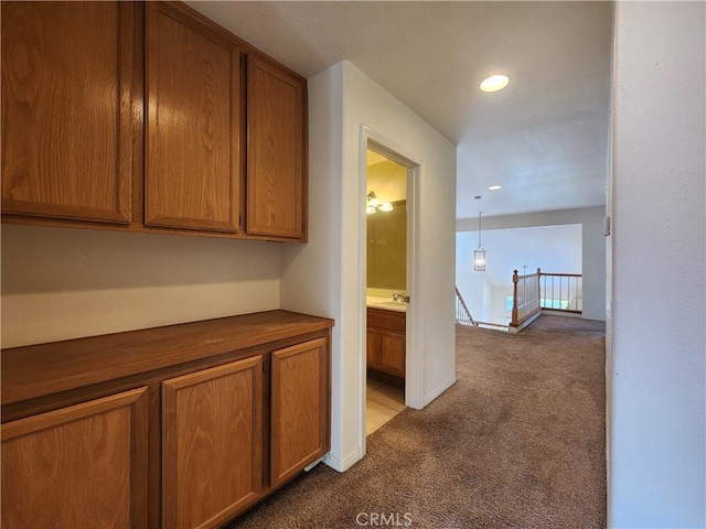 hall with an upstairs landing, recessed lighting, a sink, and light colored carpet