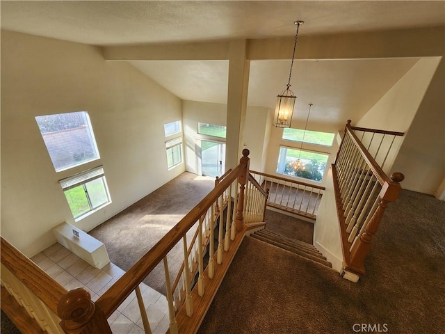 stairway with vaulted ceiling with beams, carpet, tile patterned flooring, and a wealth of natural light