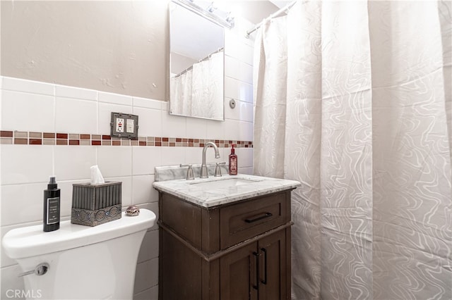 bathroom featuring toilet, curtained shower, vanity, and tile walls