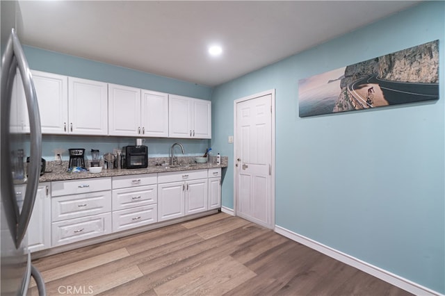 kitchen featuring white cabinets, light wood-type flooring, and stainless steel refrigerator