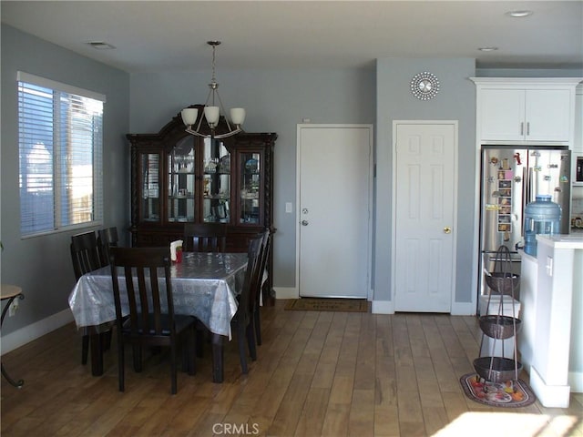 dining area with dark hardwood / wood-style flooring and an inviting chandelier