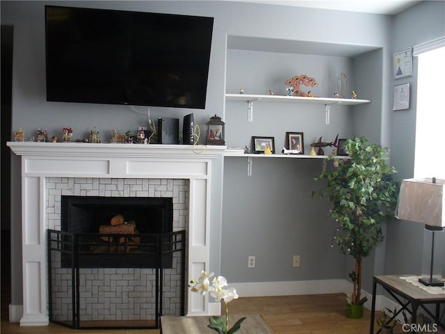 living room with a brick fireplace and hardwood / wood-style flooring