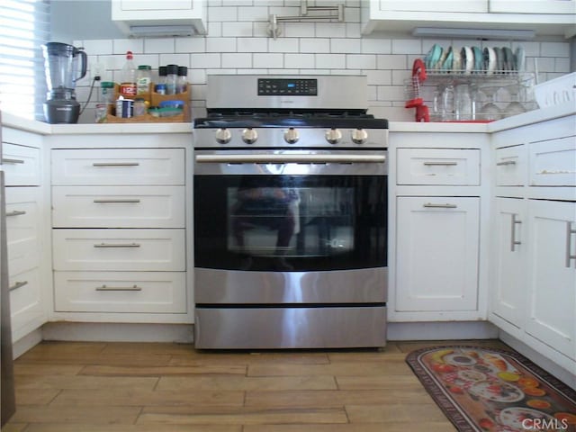 kitchen featuring tasteful backsplash, white cabinets, and stainless steel range with gas cooktop