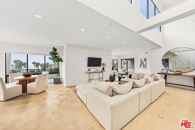 living room with baseboard heating, a healthy amount of sunlight, and a high ceiling