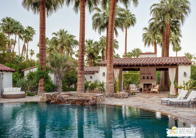 view of pool featuring an in ground hot tub, an outdoor fireplace, and a patio