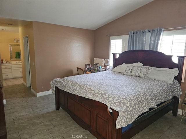 bedroom featuring ensuite bathroom and vaulted ceiling