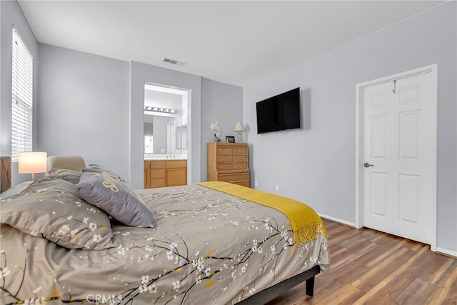 bedroom with ensuite bathroom and dark hardwood / wood-style floors