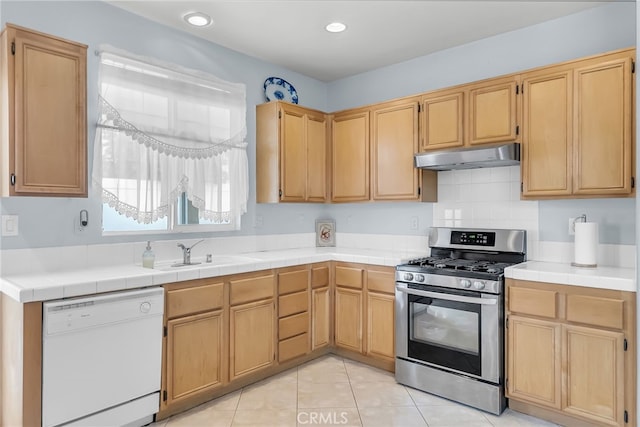 kitchen featuring light tile patterned floors, stainless steel range with gas stovetop, tile counters, dishwasher, and sink