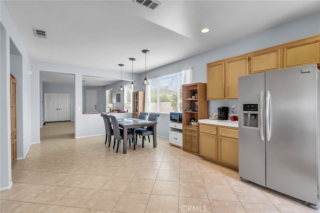 kitchen with stainless steel refrigerator with ice dispenser, light tile patterned flooring, black microwave, and pendant lighting