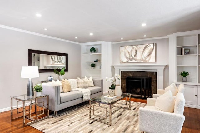 living room featuring a tiled fireplace, ornamental molding, and light hardwood / wood-style flooring